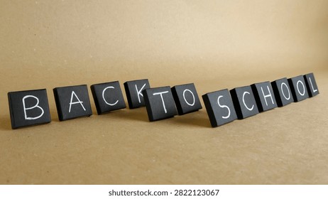 Black square blocks forming the Back to School message on a light brown background, signifying the start of the academic year