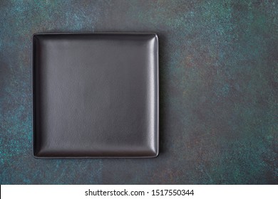 Black Square Plate On Dark Background. Top View, With Copy Space