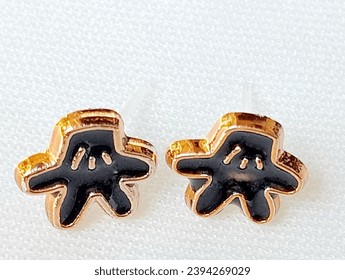 Black starfish shaped earrings placed on a white background. Close -up shot of the earrings. - Shutterstock ID 2394269029