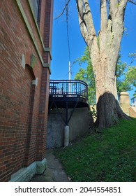 A Black Steel Balcony Running Of The Back Of A Building. There Is A High Cement Slab That Is Stabilizing The Elevated Deck.