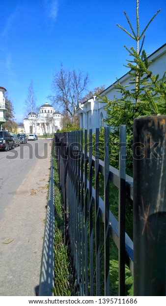 Black steel\
fence. Orthodox church, the road to the temple, landscape. St.\
Sophia Cathedral on the horizon. Parked cars by the roadside.\
Bright sunny summer day. Welded fence\
design.