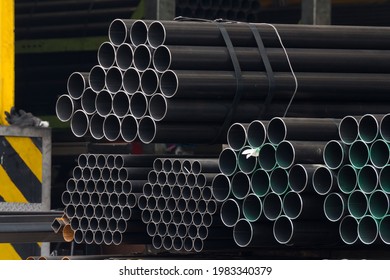 Black Steel Pipes On Shelf In Stock Yard Of Factory.