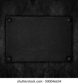 black steel plate with screws on abstract rough background