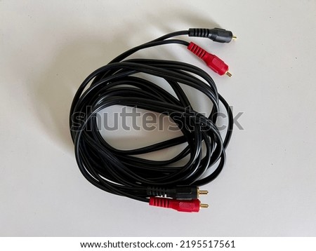Black, stereo audio cable with red and black plastic covers over gold-plated phono connectors on both ends, on white surface
