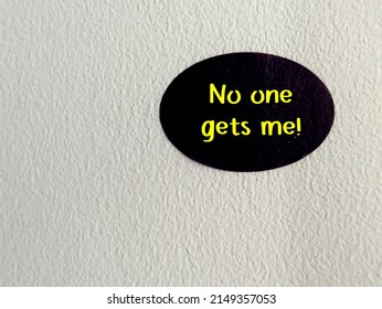 Black sticker on copy space wall background with handwritten text NO ONE GETS ME, concept of being around people and feel misunderstood