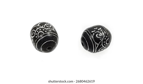Black stone beads with a silver pattern on a white background.