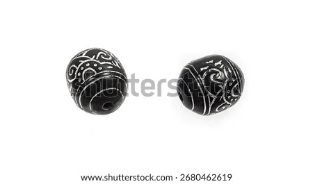 Black stone beads with a silver pattern on a white background.