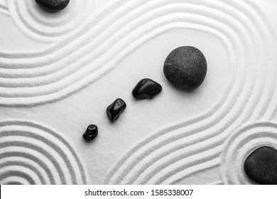Black stones on sand with pattern, top view. Zen, meditation, harmony