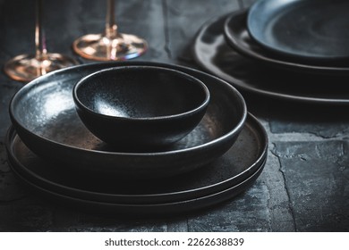 Black stoneware plates and bowls on a rustic black table - Powered by Shutterstock