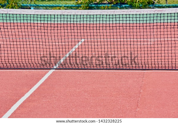 Black\
stretched net on red tennis court for\
game