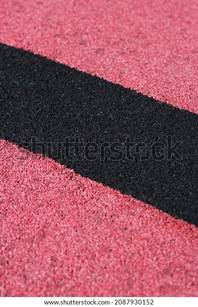 Black strip on road\
covering with rubber crumb for a sports ground. Red synthetic\
flooring, asphalt surface coating for playground. Automotive track\
for high speed cars