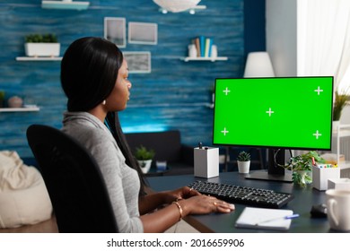 Black student discussing university courses during online videocall meeting conference looking at mock up green screen chroma key computer with isolated display. African woman working remote from home - Powered by Shutterstock