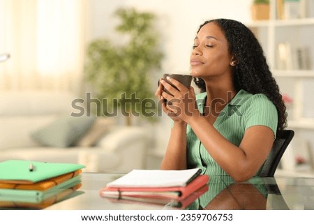 Black student relaxing drinking coffee sitting and breathing at home