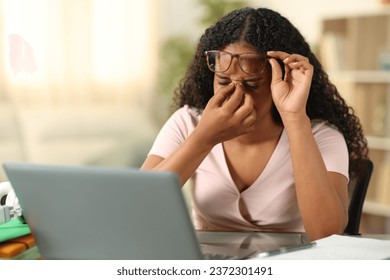 Black student suffering eyestrain studying with a laptop at home