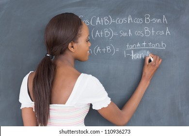 Black Student Writing On A Blackboard In A Classroom