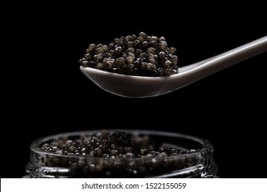 Black sturgeon caviar on a spoon. Luxurious black caviar. Sturgeon caviar in a glass jar