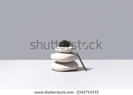 Black sturgeon caviar on white stones and gray background