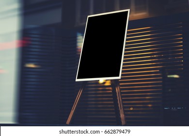 Black stylish chalkboard with mock up copy space are for your text message or advertising promotional content, empty presentation wooden board standing on the glass storefront