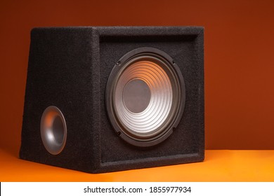 Black subwoofer speaker car audio music system on orange background