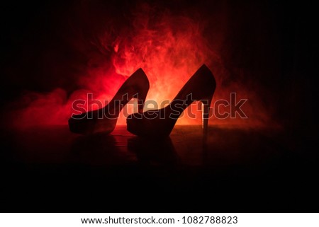 Black suede high heel women shoes on dark toned foggy background. Close up. Women power or women domination concept. Selective focus