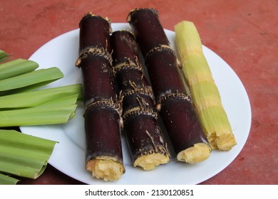 Black Sugarcane Stem Cuttings And Leaves In Red Background