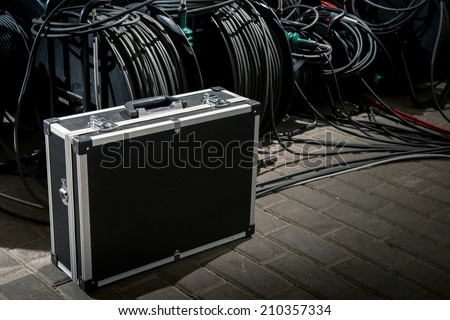 Black suitcase for professional video and audio equipment close to the black cable tangling.