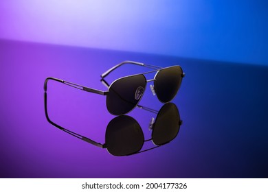 Black Sunglasses On Blue Reflective Surface, Closeup. Product Photography And Fashion Concept