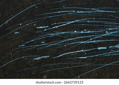 The black surface texture with a randomly spread blue abstract scratch pattern creates a dramatic and artistic impression.