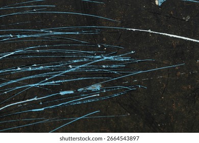 The black surface texture with a randomly spread blue abstract scratch pattern creates a dramatic and artistic impression.