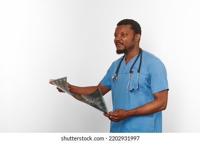 Black Surgeon Doctor Bearded Man In Blue Coat With Stethoscope Holds X Ray Image, Isolated On White Background. Pensive Black African American Practicing Radiologist Portrait, Confident Look To Xray