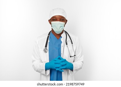 Black Surgeon Doctor Man In Blue White Coat Blue Gloves White Cap And Surgeon Mask With Stethoscope Isolated On White Background. Friendly Black African American Practicing Surgeon Portrait