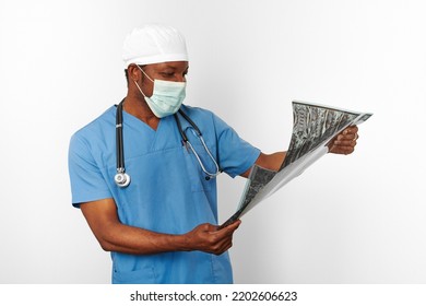 Black Surgeon Doctor Man In Blue Coat White Cap And Surgeon Mask Holds X Ray Image Isolated On White Background. Pensive Adult Black African American Practicing Surgeon Portrait, Thoughtful Look