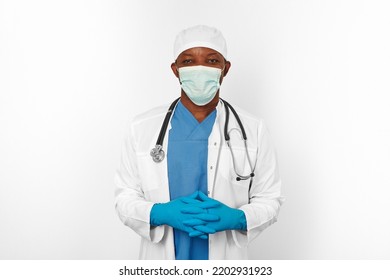 Black Surgeon Doctor Man In Blue White Coat Blue Gloves White Cap And Surgeon Mask With Stethoscope Isolated On White Background. Friendly Black African American Practicing Surgeon Portrait