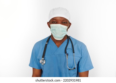 Black Surgeon Doctor Man In Blue Coat White Cap And Surgeon Mask With Stethoscope Isolated On White Background. Focused Adult Black African American Practicing Surgeon Portrait, Concentrated Look