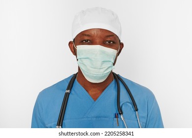 Black Surgeon Doctor Man In Blue Coat White Cap And Surgeon Mask With Stethoscope Isolated On White Background. Focused Adult Black African American Practicing Surgeon Portrait, Concentrated Look