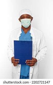 Black Surgeon Doctor Man In White Coat Cap And Surgeon Mask Holds Medical Records With Diagnosis On Clipboard, Isolated On White Background. Adult Black African American Practicing Surgeon Portrait