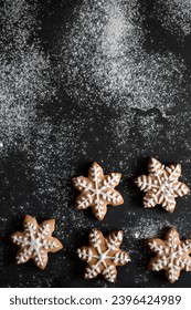 Black table background with flour and star gingerbread cookie decorated with sugar glaze, top view, copy space. - Shutterstock ID 2396424989