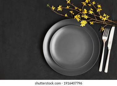 Black table setting. Yellow flowers and black plate on a dark gray background. Easter. Copy space, top view, flat lay. - Powered by Shutterstock