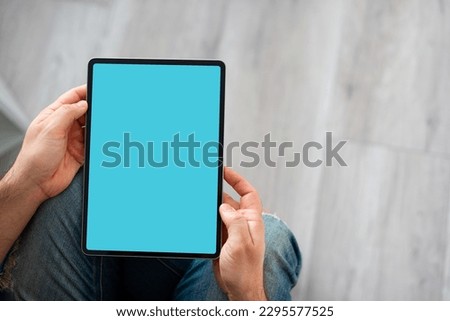 Black tablet device mockup in male hands. Top view with copy space.