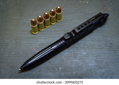 Black Tactical Pen And 9mm Rounds On A Wooden Box.