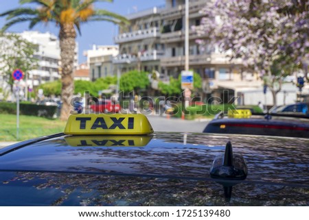 Black taxi cars with yellow standard signs on top parked or stoped on busy city street, taxi service.