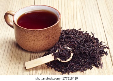 Black Tea In A Cup And Dried Leaves On Wooden Background