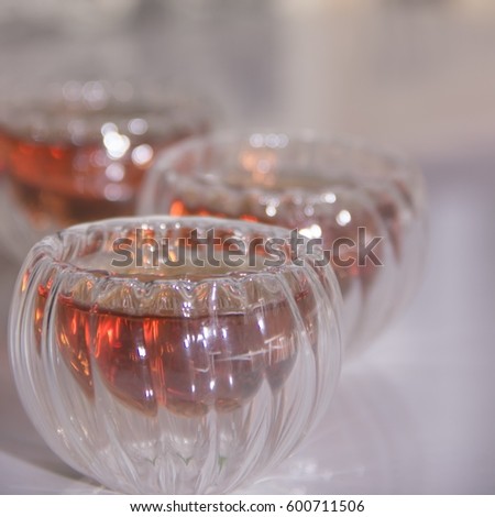 Black tea in a glass transparent bowls. Few small cups of tea on table. Glass piala with double walls, double-bottomed bowl. Meal, aperitif, repast. Square. Blurred background