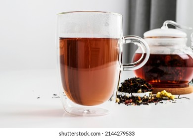Black tea in a transparent thermos mug on the table close-up. Visual for tea sample. Method of brewing and storage. Welding in a transparent teapot. tea color