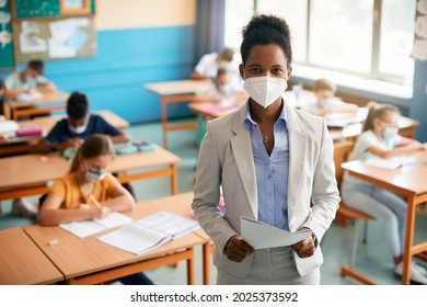 Black Teacher Wearing Face Mask While Teaching Elementary Students At School During COVID-19 Pandemic. 