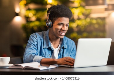 Black Teen Gamer Playing in Video Game on Laptop Computer, Sitting in Headphones in Cafe, empty space