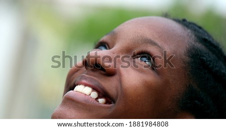 Black teen girl opening eyes to sky. African mix race adolescent woman smiling with HOPE and FAITH
