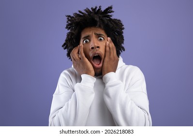 Black teen guy feeling scared, shouting in panic on violet studio background. Terrified African American teenager suffering from phobia, being scared or frightened. Negative human emotions concept