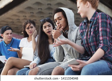 Black Teen Guy Smoking Cigarette, His Friends Judging Him. Social Issues Between Young People