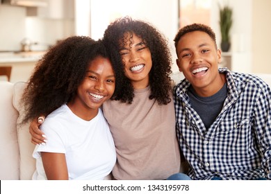 Black teen and young adult brother and sisters smiling to camera, close up
